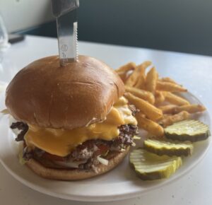 Burger, fries, and pickles on a plate.