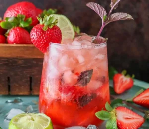 iced strawberry mocktail garnished with fresh lime, mint leaves, and ripe berries.